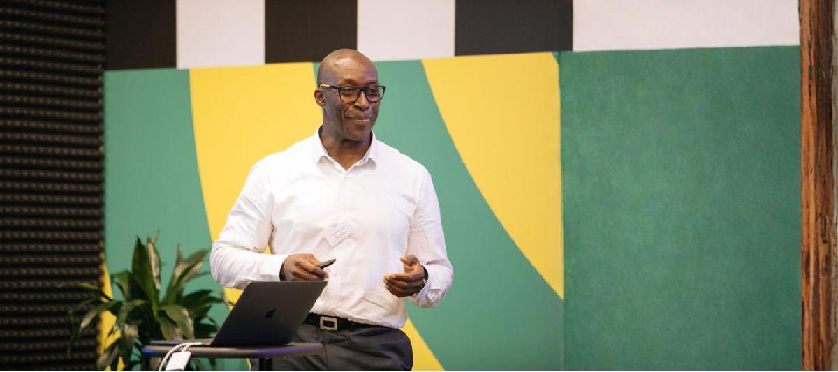 Fredi Nonyelu speaking at a conference, holding a microphone on stage